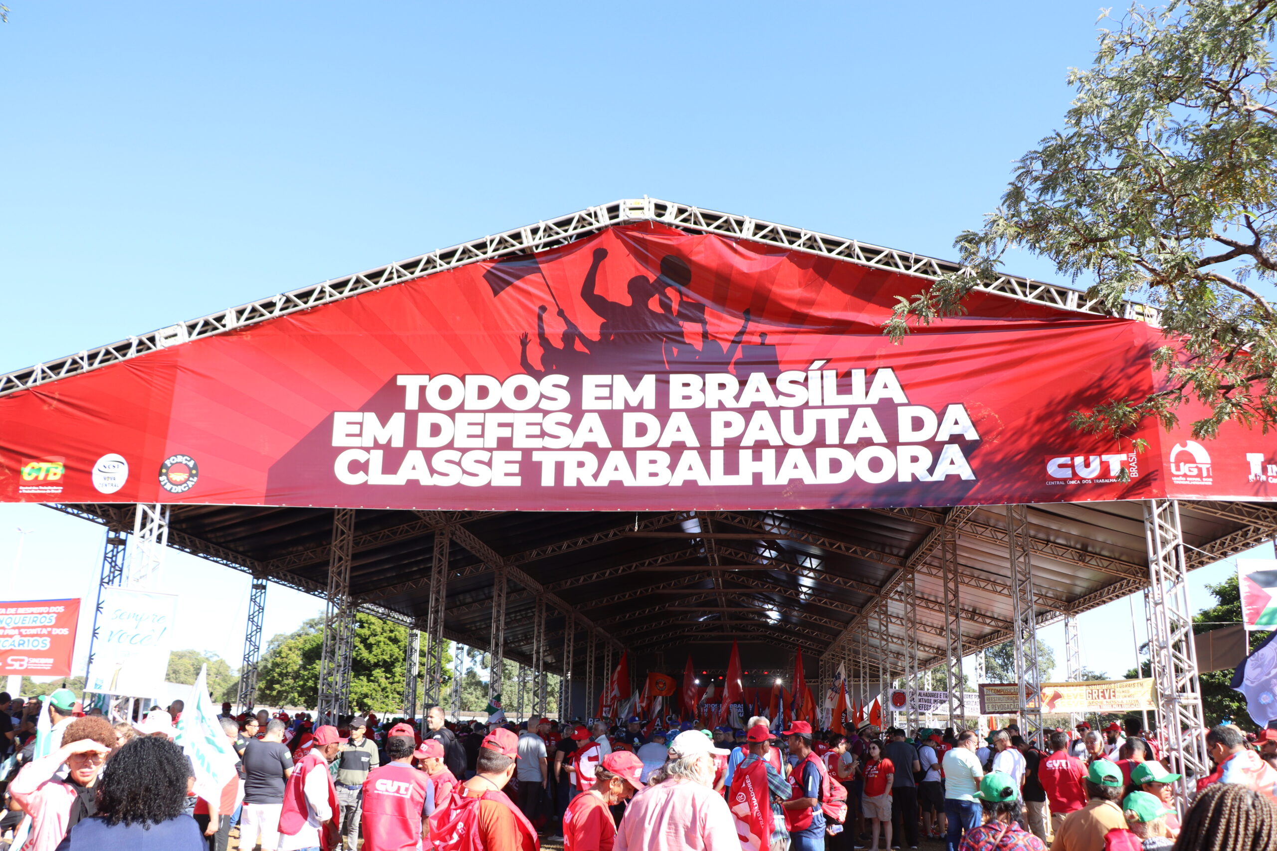 Tenda vermelha escrita "todos em Brasília em defesa da pauta da classe trabalhadora"