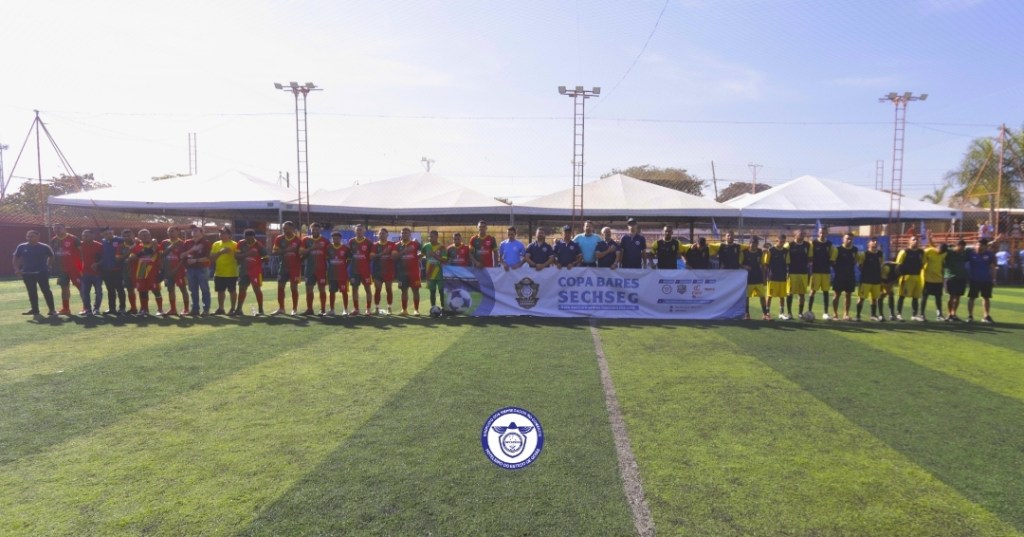 Times frango gaúcho e oficina cervejaria na final antes de competirem para a taça ouro em fila no gramado, junto ao sindicato que segura faixa.